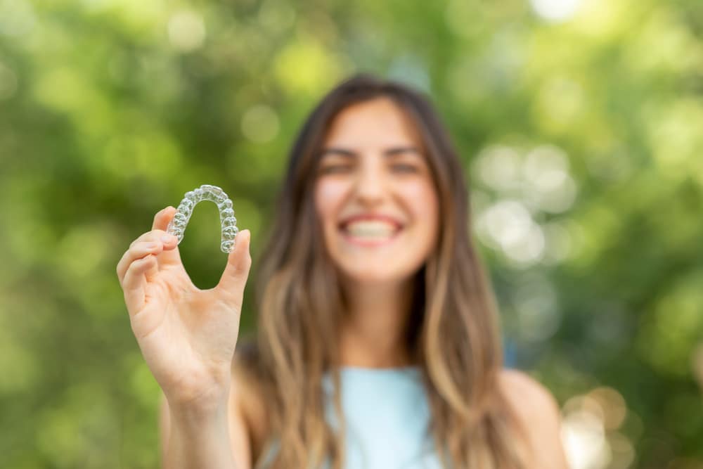 young woman holding invisalign aligner